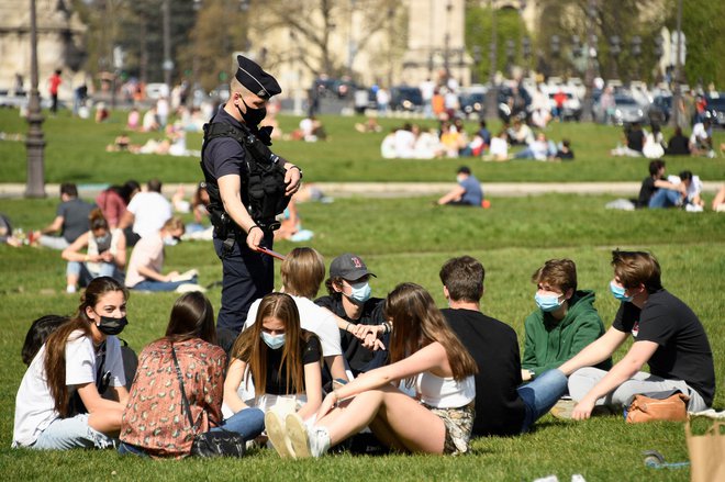 V Parizu policisti nadzorujejo skupine ljudi, ki uživajo v sončnem pomladnem dnevu na travi pred hotelom des Invalides zadnji dan pred ponovnim popolnim zaprtjem javnega življenja. FOTO: Bertrand Guay/Afp