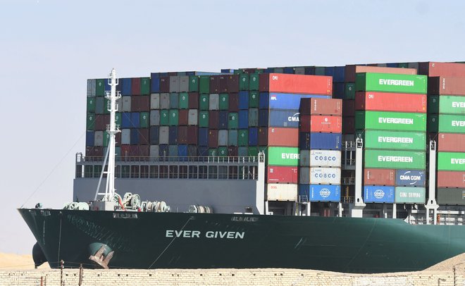 Kontejnerska ladja Ever Given je še vedno na pregledu sredi Sueškega prekopa, s tem pa z dostavo zamuja tudi okoli 18.000 kontejnerjev. FOTO: Ahmad Hassan/AFP