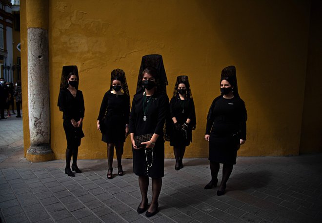 Ženske oblečene v črnino stojijo na ulici v Sevilli, kljub temu, da je že drugo leto zapored zaradi koronavirusa odpovedana verska procesija ob Svetem tednu. FOTO: Cristina Quicler/Afp