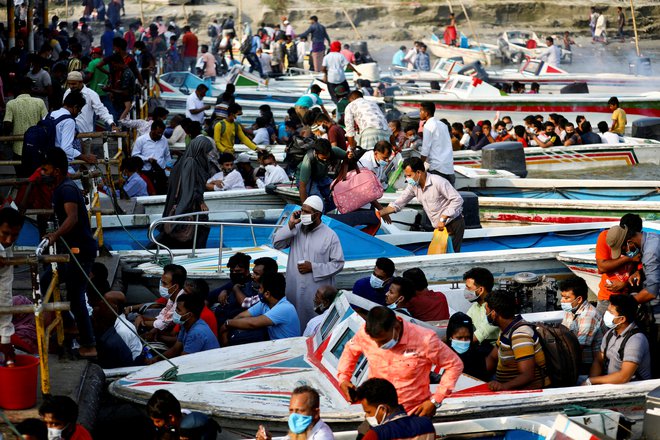 Migranti in delavci zapuščajo mesto s hitrimi čolni pred pred začetkom vsakodnevne policijske ure, ki so jo uvedli zaradi zajezitve koronavirusa v pristanišču Mawa v Bangladešu. FOTO: Mohammad Ponir Hossain/Reuters