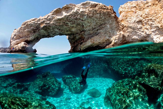 Louis Hadjioannou se potaplja, da bi fotografiral korale v kristalno čisti vodi v Ayia Napi, na jugovzhodni obali Cipra. Ciprski morski ekolog spremlja vpliv podnebnih sprememb na občutljivo favno, saj si zadnjih devet let sistematično zapisuje učinek naraščajočih morskih temperatur na korale v bližini rta Greko ter si prizadeva za ozaveščanje pri reševanju morske raznolikosti ciprskih voda za naslednjo generacijo otočanov. FOTO: Emily Irving-swift/Afp
