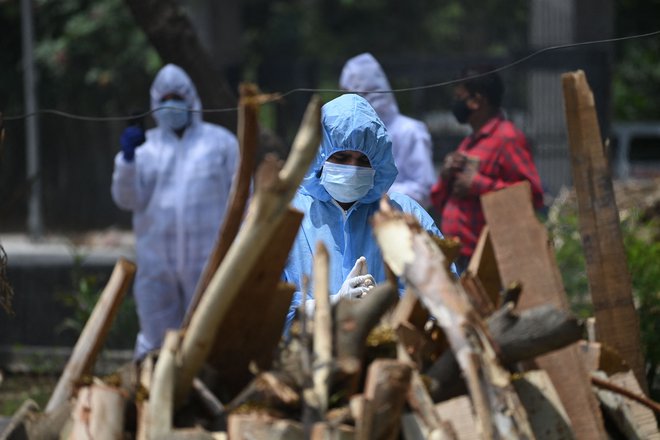 Sorodnik opravlja zadnje obrede pred upepeljevanjem osebe, ki je umrla zaradi koronavirusa v New Delhiju. FOTO: Sajjad Hussain/AFP