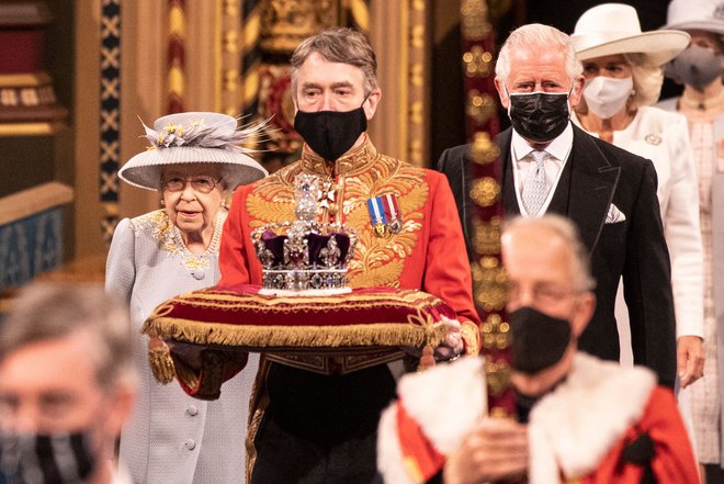Britanska kraljica Elizabeta II. je s predstavitvijo programa vlade odprla novo zasedanje britanskega parlamenta. Pri tem je kot prednostno nalogo poudarila okrevanje po pandemiji. To je bil za kraljico prvi večji javni dogodek po smrti njenega moža princa Filipa. FOTO: Richard Pohle/Afp