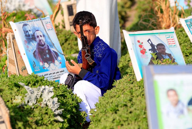 Jemenski deček sedi na grobu svojih staršev na pokopališču v Sani. FOTO: Mohammed Huwais/Afp<br />
&nbsp;