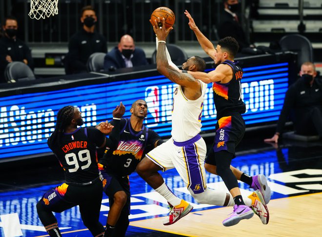 LeBron James je ob najboljšemu strelcu Phoenixa Devinu Bookerju položil žogo v koš, a končnico so branilci naslova LA Lakers začeli z zaostankom z 0:1 v zmagah. FOTO: Mark J. Rebilas/Usa Today Sports