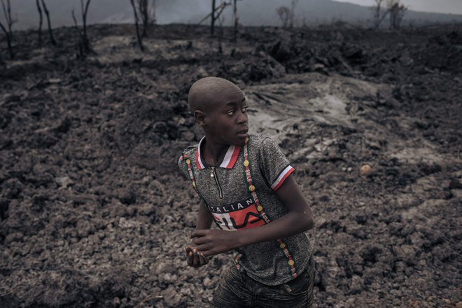 Otrok teče po strjeni in ohlajeni lavi, ki jo je izbruhnil vulkan Nyiragongo v Gomi, glavnem mestu province Severni Kivu. Najaktivnejši vulkan v Afriki, ki se nahaja v narodnem parku Virunga, je izbruhnil 22. maja. Umrlo je 32 ljudi. FOTO: Alexis Huguet/Afp