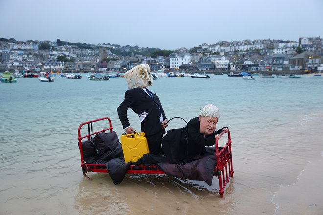 Pred vrhom G7 so v pristanišču v Cornwallu aktivisti podnebne akcijske skupine Ocean Rebellion upodobili britanskega premierja Borisa Johnsona in gospoda, ki predstavlja industrijo fosilnih goriv. FOTO: Tom Nicholson/Reuters