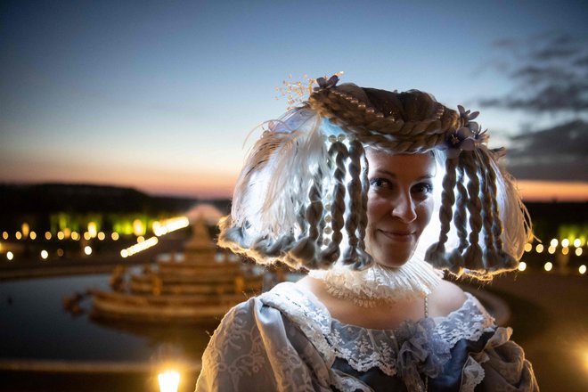 Ženska, oblečena v baročni kostum, pozira fotografu v parku kraljeve palače v Versaillesu jugozahodno od Pariza med ponovnim odprtjem spektakularne Nočne fontane (Grandes Eaux Nocturnes). FOTO: Alain Jocard/Afp<br />
&nbsp;
