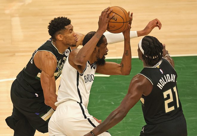 Kevin Durant (z žogo) prodira ob Giannisu Antetokounmpu (levo) in Jrueju Holidayu na šesti tekmi v Milwaukeeju. FOTO: Jonathan Daniel/AFP