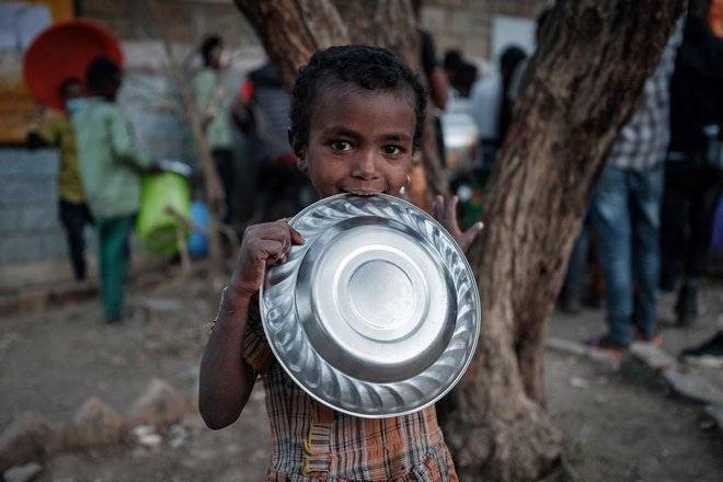 Otrok, ki je pobegnil pred nasiljem iz etiopske regije Tigray, pred osnovno šolo May Weyni čaka na večerjo, saj le ta predstavlja edini dnevni obrok. OŠ se je spremenila v taborišče za notranje razseljene osebe. FOTO: Yasuyoshi Chiba/Afp