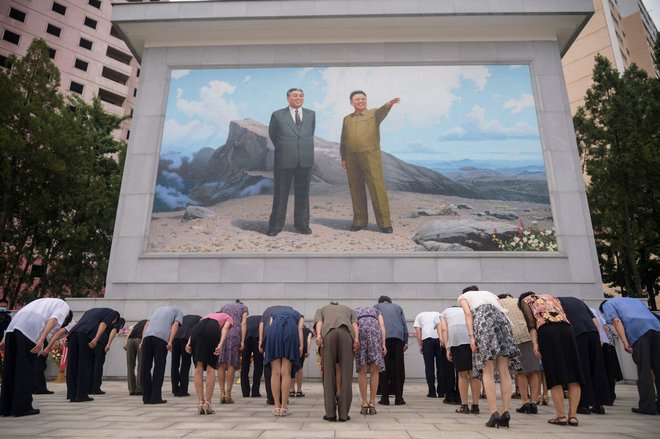 Ljudje se poklonijo pred mozaikom portretov pokojnih severnokorejskih voditeljev Kim Il Sunga in Kim Jong Ila v Pjongčangu ob 27. obletnici smrti Kim Il Sunga, FOTO: Kim Won Jin/Afp