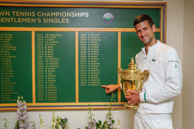 Novak Đoković je s pokalom v rokah ponosno pokazal na svoje ime na tabli z zmagovalci. FOTO: Thomas Lovelock/AFP