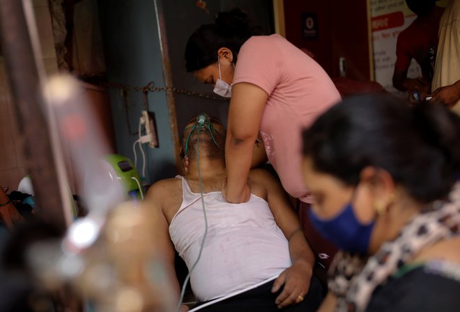 V indijskem mestu Ghaziabad Manisha Bashu masira prsi svojega očeta, ki ima težave z dihanjem, potem ko je izgubil zavest kljub dodatnem kisiku. FOTO: Adnan Abidi/Reuters<br />
&nbsp;