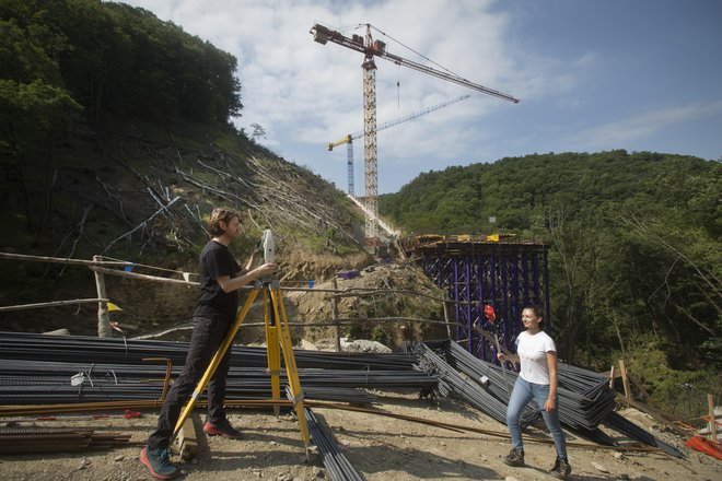 Geodeta Gregor Repar in Nina Stajnko iz podjetja Garnol s tahometrom merita in računata koordinate za nastajajoči zadnji opornik mostu čez Glinščico. Vsak meter mostu tehta 65 ton, zato je natančnost nujna. FOTO: Jure Eržen/Delo