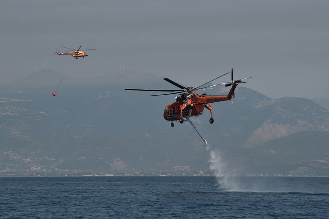 Grki se proti ognjenim zubljem bojujejo tudi z gasilskimi letali in helikopterji. Skupno sta aktivirani dve letali, pet helikopterjev, na delu je skoraj 300 gasilcev. FOTO: Louisa Gouliamaki/AFP