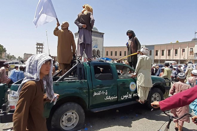 Talibski borci na poškodovanem vozilu policije v mestu Kandahar.<br />
FOTI: AFP