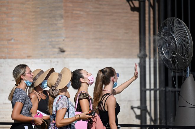 Skupina žensk se med vročinskim valom hladi pred ventilatorjem, ko stojijo v vrsti pred vhodom v rimski Kolosej. Na Siciliji je 11. avgusta padel nov evropski rekord, saj je termometer pokazal kar 48,8 stopinje Celzija. FOTO: Alberto Pizzoli/Afp