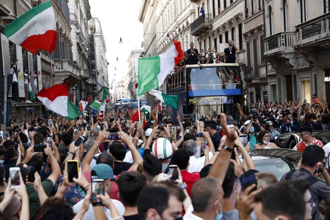 Z nogometaši je julija navdušene rojake pozdravljal tudi teniški igralec Matteo Berrettini. Najprej se je zdelo, da parade zaradi strahu pred širjenjem okužb ne bo, a so odgovorni na koncu popustili in popeljali avtobus z junaki po nekaj rimskih ulicah. FOTO: Guglielmo Mangiapane/Reuters