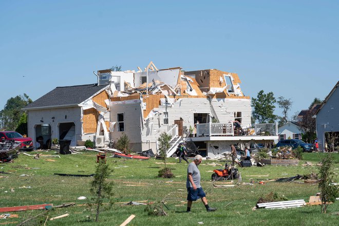 Moški se sprehaja ob hiši v New Jerseyju, ki jo je poškodoval tornado, potem ko je območje preplavilo rekordno število padavin, ki so jih prinesli ostanki orkana Ida. FOTO: Branden Eastwood/Afp<br />
&nbsp;