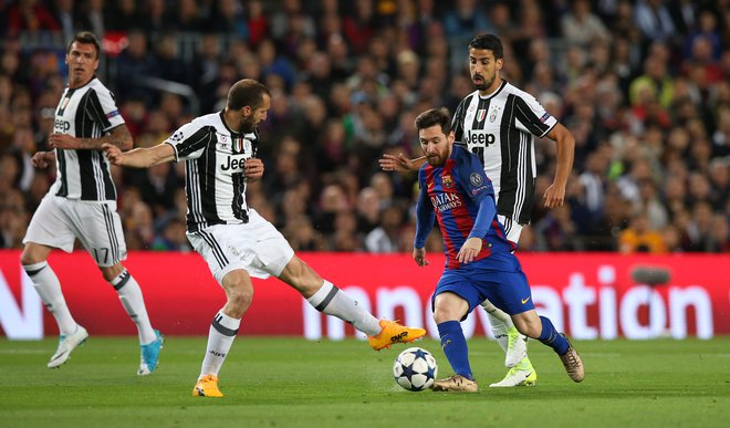 Argentinski kapetan Lionel Messi (desno) v boju z italijanskim Giorgiem Chiellinijem na tekmi&nbsp;lige prvakov med Barcelono in Juventusom. FOTO: Albert Gea/Reuters