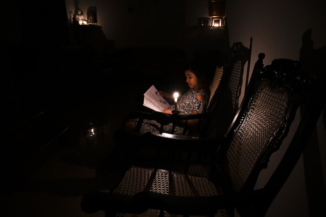 S pomanjkanjem dobave električnega toka se sooča več azijskih držav. Na fotografiji dekle iz Šrilanke, ki bere knjigo ob sveči; oblasti so namreč prilagodile porabo električne energije. FOTO: Ishara S. Kodikara/Afp