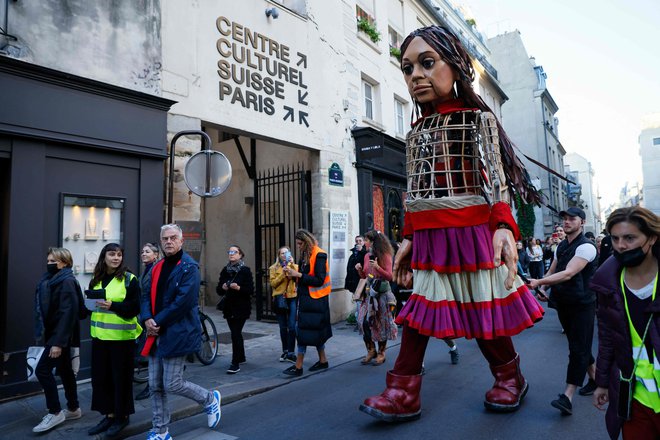Velikanska lutka, ki so jo poimenovali Mala Amal, predstavlja sirsko deklico begunko. Mala Amal, ki je sinonim za milijone razseljenih otrok po vsem svetu, je začela svojo 8000 km dolgo pot v Turčiji. Trenutno se sprehaja po ulicah Pariza, končni cilj pa je Velika Britanija. FOTO: Thomas Samson/Afp
