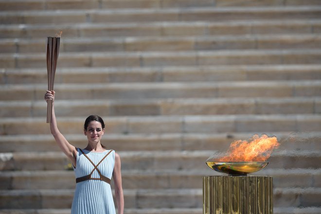 Grška igralka Xanthi Georgiou, oblečena v antično grško svečenico, drži olimpijsko baklo na marčevski slovesnosti pred poletnimi OI v Tokiu. FOTO: Aris Messinis/AFP
