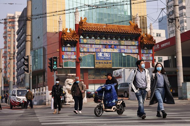 Ljudje na ulicah Pekinga ob začetku novega delovnega tedna. FOTO: Thomas Peter/Reuters
