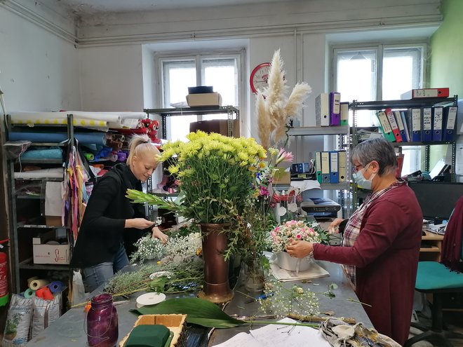 Cvetličarke so hitele od pulta do delovnega prostora v ozadju in pripravljale ikebane, izbirale cvetje in dekoracijo za šopke. FOTO: Nataša Čepar/Delo
