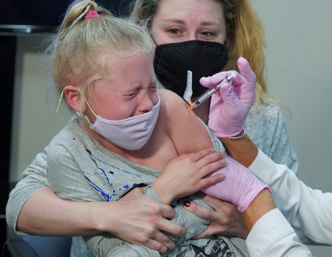 V ameriškem mestu Storrs je 7-letna Emma Ingle, ki sedi v naročju svoje matere Kim Obert, prejela svoj prvi odmerek Pfizer cepiva proti koronavirusu. FOTO: Michelle Mcloughlin/Reuters

&nbsp;
