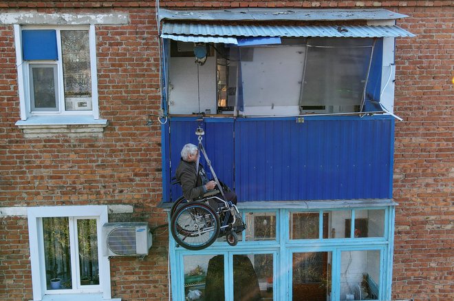 V ruskem mestu Timashevsk se Alexander Yudin vzpenja na balkon svojega stanovanja v tretjem nadstropju z dvigalom, ki ga je izdelal sam. Električar, ki je izgubil nogo v prometni nesreči pred nekaj desetletji, si je pred tremi leti poškodoval še drugo nogo, zato je bil primoran zgraditi balkonsko dvigalo na sončno energijo. FOTO: Sergej Pivovarov/Reuters

&nbsp;
