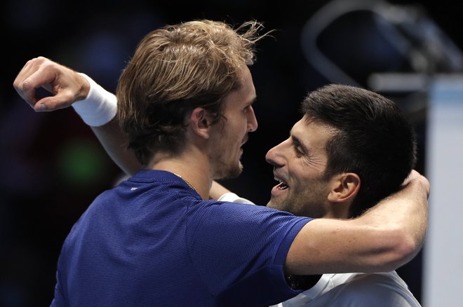 Alexander Zverev in Novak Đoković v objemu po epskem polfinalu v Torinu. FOTO: Guglielmo Mangiapane/Reuters
