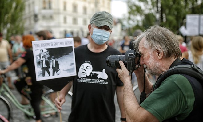 Tone Stojko fotografira protestnika, ki nosi njegovo fotografijo iz leta 1988. FOTO: Blaž Samec/Delo
