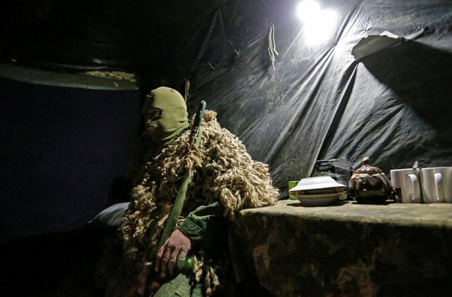 Ostrostrelec iz uporniške Doneške ljudske republike nadzira razmejitveno črto, ki utegne postati zelo vroča fronta nove hladne vojne. FOTO:&nbsp;Aleksander Ermočenko/Reuters
