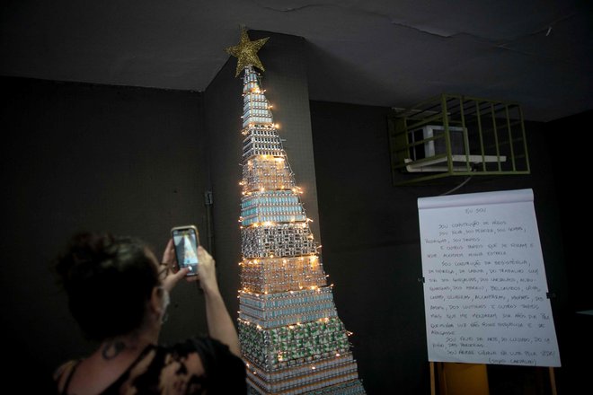 A woman takes photos of a christmas tree made with COVID-19 and Flu vaccine vials at the Public Health Basic Unit &quot;Ernani Agricola&quot;, in the Lapa neighborhood in Rio de Janeiro, Brazil, on December 9, 2021. - Health professionals of the unit made the Christmas tree as a way to raise awareness on vaccination locally in its neighborhood but a photo of the tree went viral on Twitter and called attention nationwide. (Photo by MAURO PIMENTEL/AFP)
