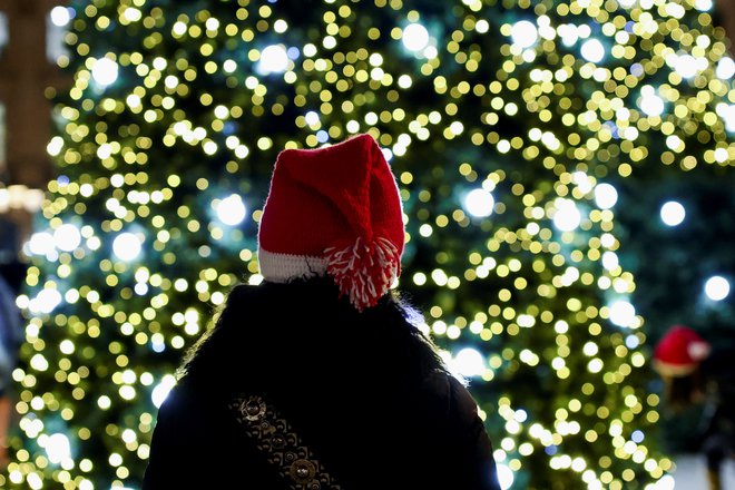 A woman with a Christmas hat stands near Christmas trees installed on the Place Vendome as part of the holiday season illuminations in Paris, France, December 8, 2021. REUTERS/Sarah Meyssonnier Foto Sarah Meyssonnier Reuters
