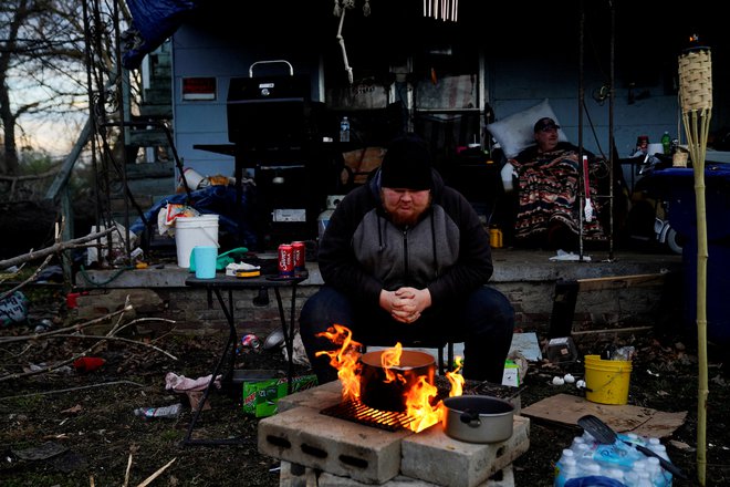 24-letni Christopher Bowlin sedi ob ognju pred svojim uničenim domom v Mayfieldu in si kuha jajca po uničujočem tornadu, ki je divjal v več ameriških zveznih državah. FOTO: Cheney Orr/Reuters


&nbsp;
