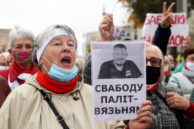 &raquo;Svoboda političnim zapornikom,&laquo; je pred dobrim letom protestnica zapisala na plakat s fotografijo opozicijskega blogerja Sergeja Tihanovskega, ki so mu v torek prisodili 18 let strogega zapora. FOTO: AFP

