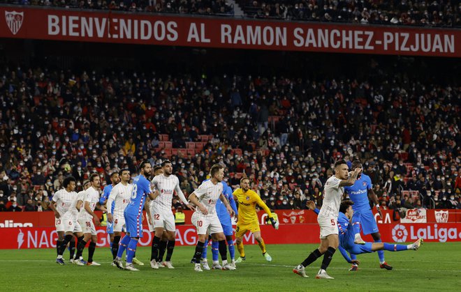Jan Oblak, v rumenem dresu, v gneči v Sevilli ni zatrl domačih nogometašev, ti so v belih dresih. FOTO: Marcelo Del Pozo/Reuters
