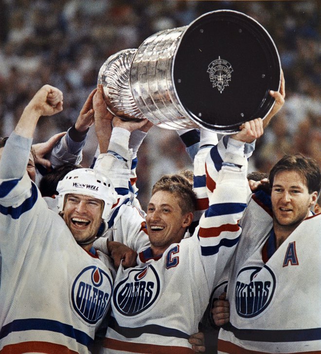 Wayne Gretzky s Stanleyjevim pokalom,&nbsp;ki ga je leta 1988 v Edmontonu osvojil ob boku Marka Messierja (levo)&nbsp;in Kevina Lowa (desno). FOTO:&nbsp;Mike Blake/Reuters
