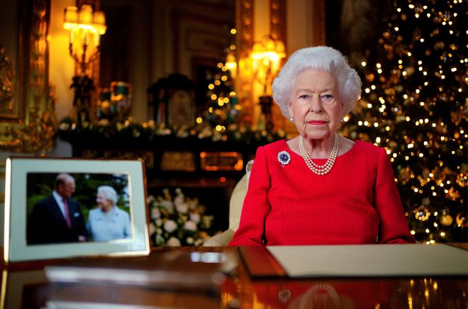 Kraljica je bila oblečena v rdečo obleko z biseri okoli vratu, na obleki je imela broško s safirjem, ki jo je nosila na poročnem potovanju ter kasneje na diamantni poroki. FOTO: Victoria Jones/Pool/Reuters
