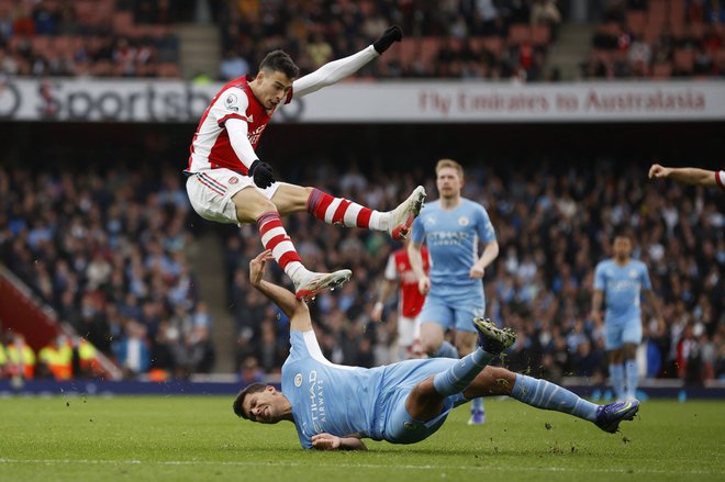 Na štadionu Emirates v Londonu je bil Manchester City srečnejši in je v sodnikovem dodatku prišel do enajste zaporedne zmage. Priigral jo je Rodi (na tleh), ki je imel kar nekaj dela z Brazilcem Gabrielom Martinellijem. FOTO: John Sibley/Reuters
