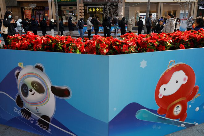 Povpraševanje po uradnih artiklih ZOI 2022 je veliko, takšna vrsta se je v sredo pred trgovino vila na ulici&nbsp;Wangfujing v Pekingu. FOTO: Carlos Garcia Rawlins/Reuters
