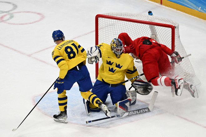 Pavel Karnauhov je ob vratarju Larsu Johanssonu&nbsp;končal v njegovi mreži med polfinalnim obračunom v Pekingu. FOTO: Anthony Wallace/AFP
