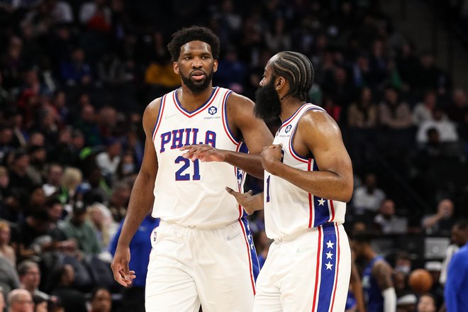 Navijači Philadelphie si po prvi tekmi, ki sta jo skupaj odigrala Joel Embiid in James Harden (desno), manejo roke. FOTO: David Berding/AFP
