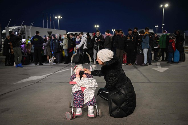 Ukrajinka govori z otrokom na meji z Romunijo. FOTO:&nbsp;Daniel Mihailescu/AFP
