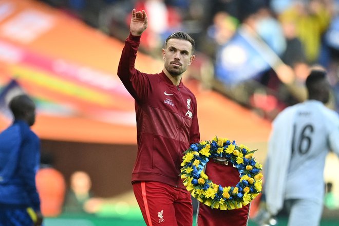 Liverpoolov kapetan Jordan Henderson je prinesel venec v barvah ukrajinske zastave. FOTO: Justin Tallis/AFP
