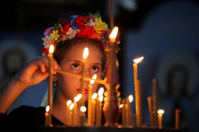 Deklica, potomka ukrajinskih priseljencev, prižiga sveče med mašo v ukrajinski pravoslavni cerkvi v Braziliji. FOTO: Diego Vara/Reuters
