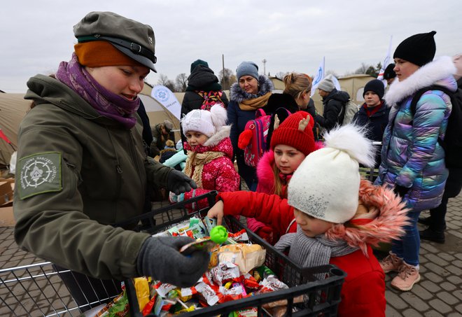 Poljski prostovoljci so otrokom razdelili nekaj sladkarij. FOTO: Fabrizio Bensch/Reuters
