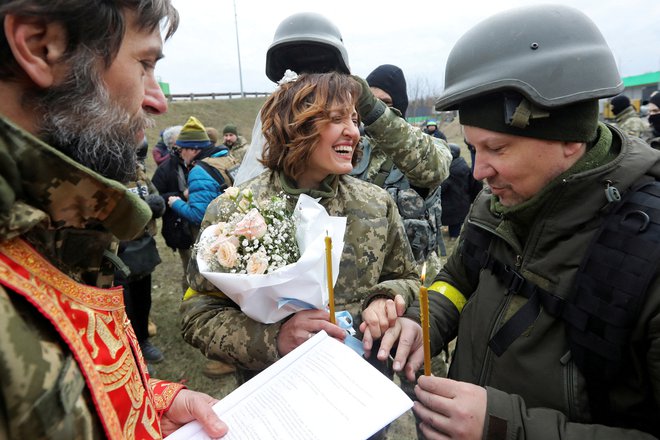 Pripadnika ukrajinskih teritorialnih obrambnih sil Lesja Ivaščenko in Valerij Fylymonov sta se poročila sredi ruske invazije kar na kontrolni točki v Kijevu. Foto: Mykola Tymchenko/Reuters
